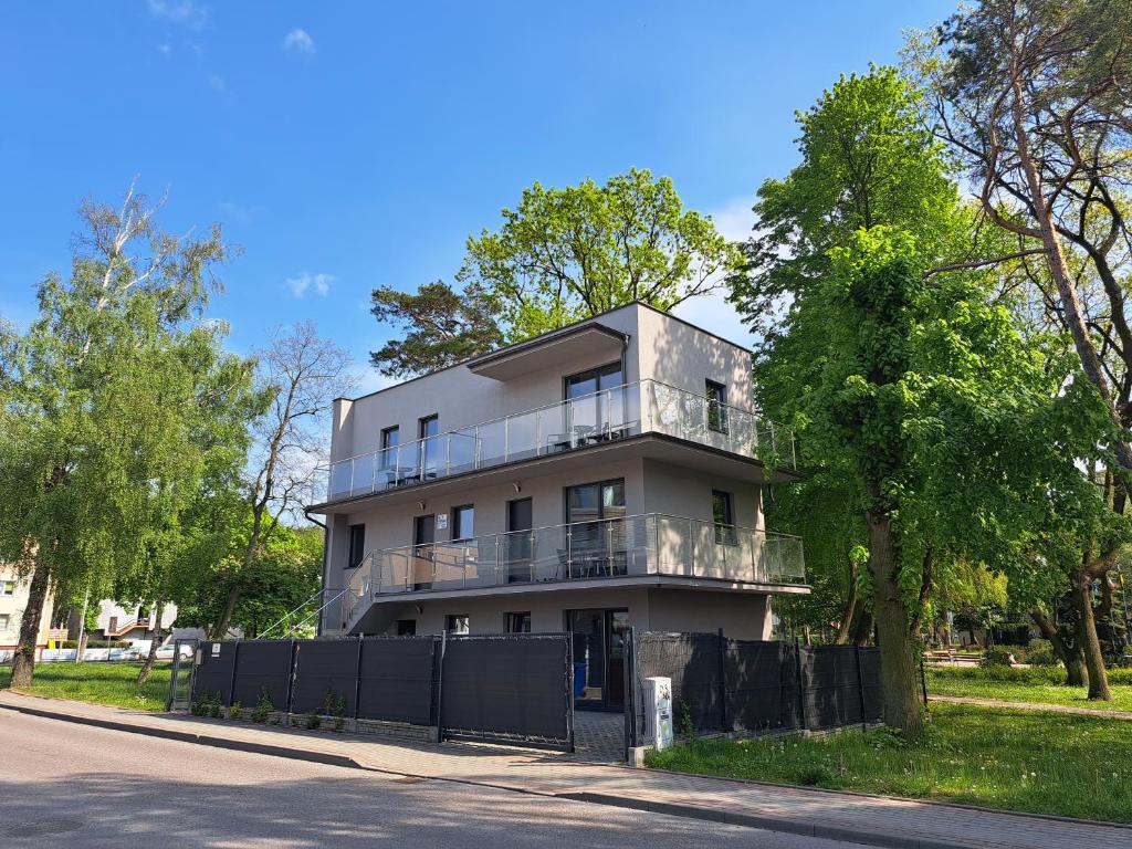 a white building with a balcony on the side of a street at Domek w Parku Hel in Hel