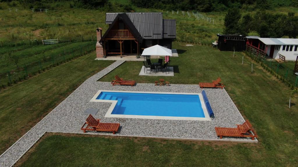 een uitzicht over een zwembad met stoelen en een huis bij Vikendica sa bazenom MAGNUM in Višegrad