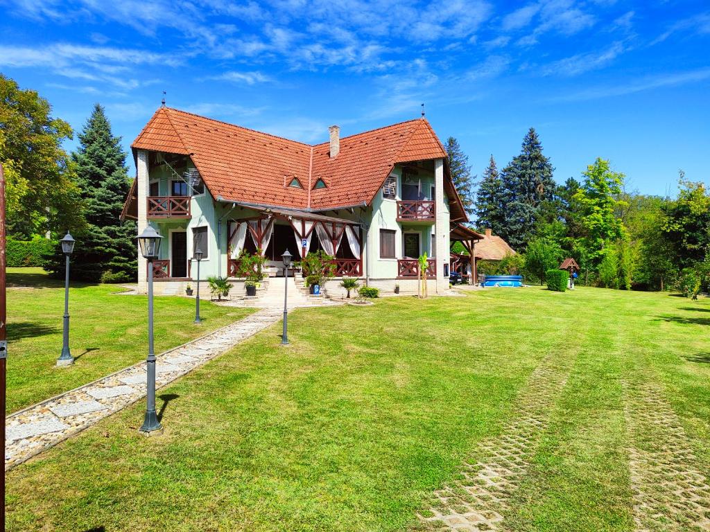 a house with a red roof on a green lawn at Balaton Garden in Balatongyörök
