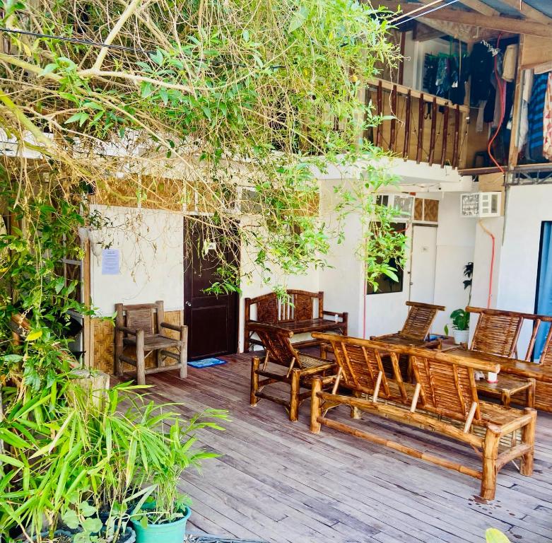 a patio with chairs and tables and trees at Babu Backpackers inn in Moalboal