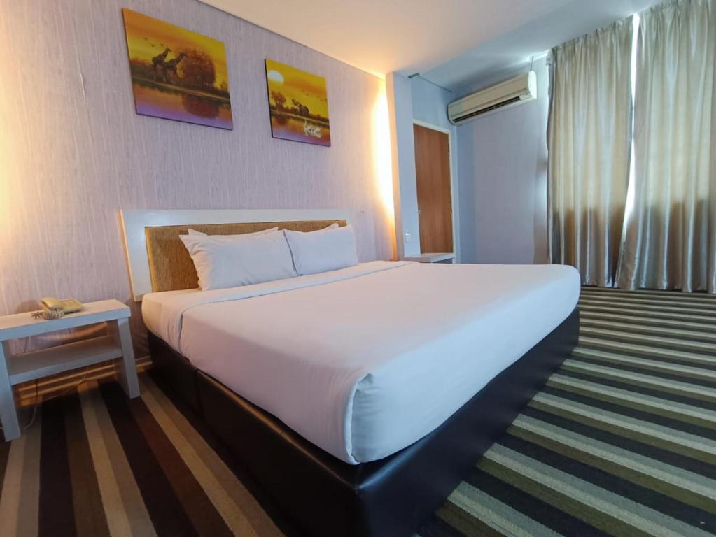 een groot wit bed in een hotelkamer bij First Residence Hotel by RVH in Cukai