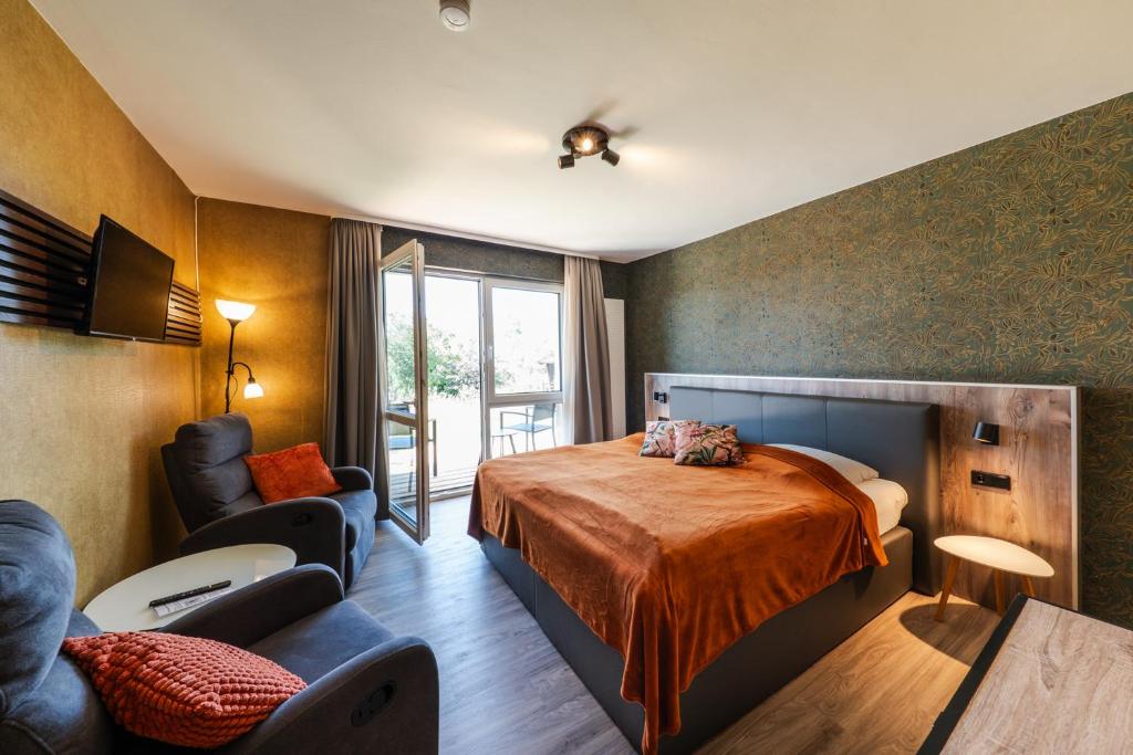 1 dormitorio con cama, sofá y TV en Berghotel Hohegeiß, en Hohegeiss