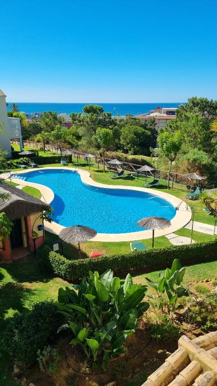 a large swimming pool with umbrellas and the ocean at Hoyo 12 Islantilla in Huelva