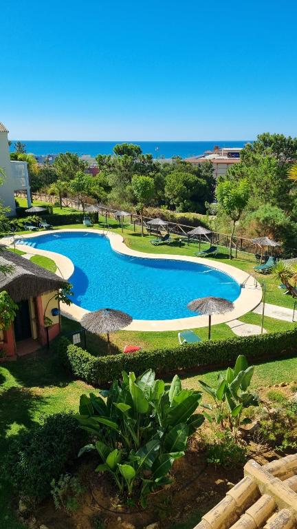 une grande piscine avec des parasols et l'océan dans l'établissement Hoyo 12 Islantilla, à Huelva