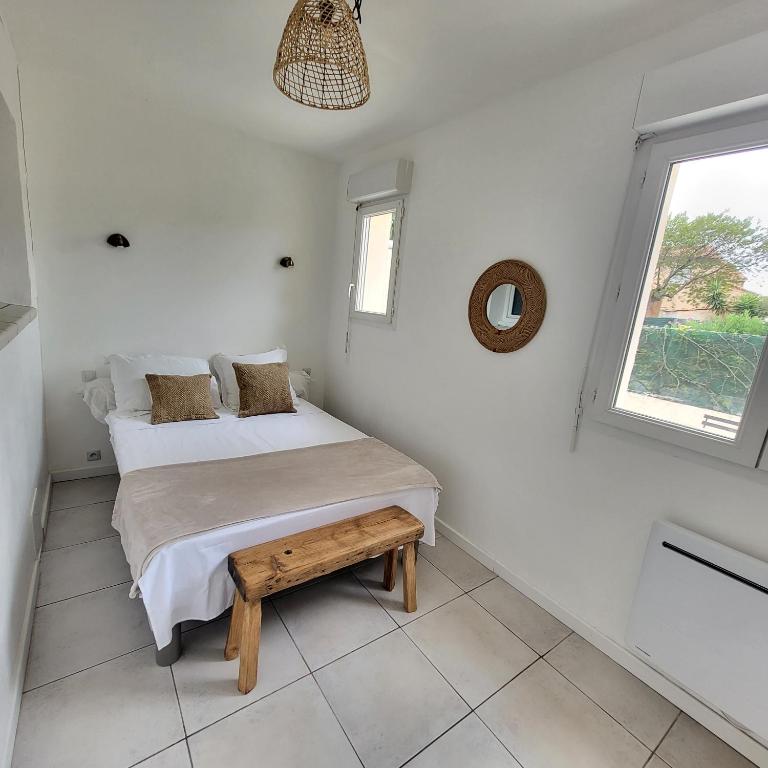 une chambre avec un lit et un banc dans l'établissement Bel appartement avec jardin de 30m2 , climatisé avec parking et arrivée autonome, à Cabestany