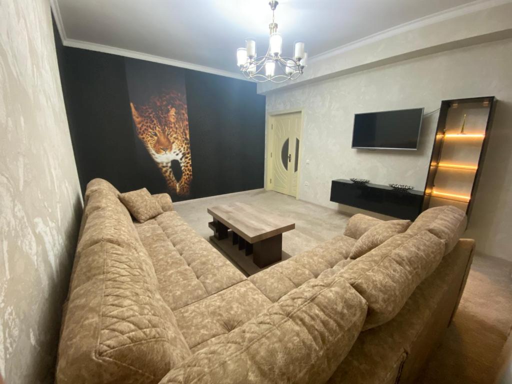 sala de estar con sofá grande y mesa en Уютная квартира, en Tashkent