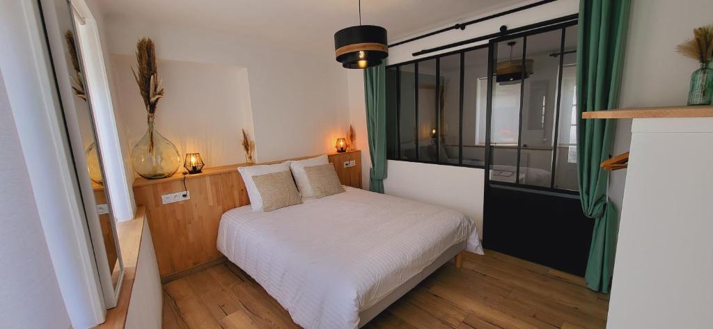 um pequeno quarto com uma cama branca e uma janela em Gîte Pontors'home Mont Saint-Michel em Pontorson