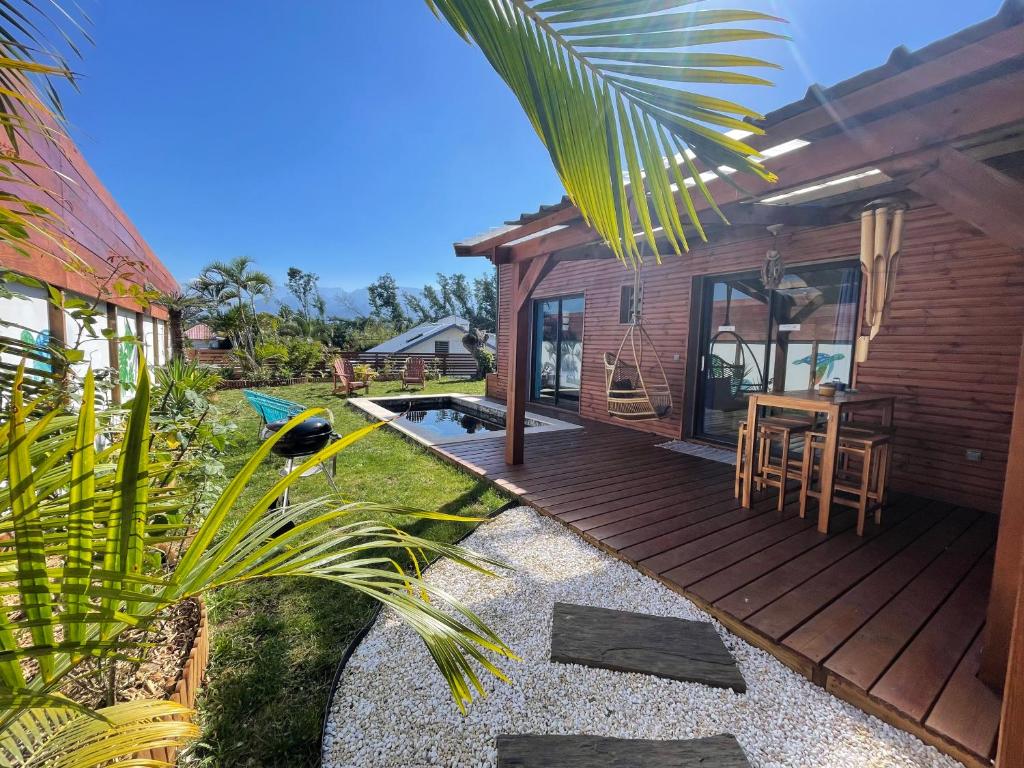 a wooden deck with a table and chairs on a house at Anaélodge piscine privée chauffée 30 degrés in Le Tampon