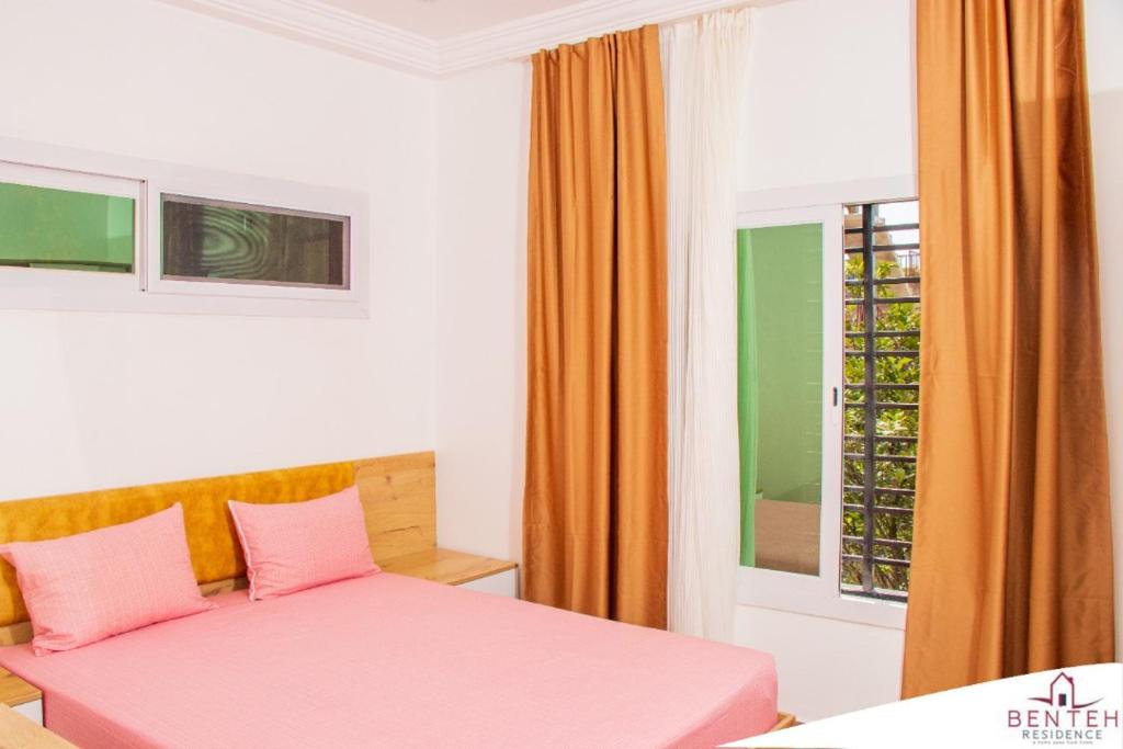um quarto com uma cama rosa e uma janela em Benteh 2 em Banjul
