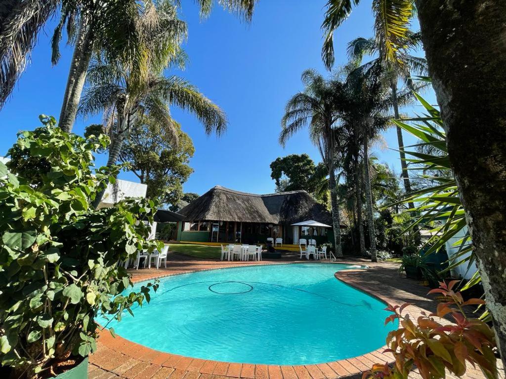 a swimming pool in front of a resort with palm trees at Villa Grande Lodge in Louis Trichardt