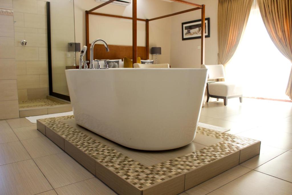 a bathroom with a bath tub on a tiled floor at SteyMorr Guesthouse in Maun