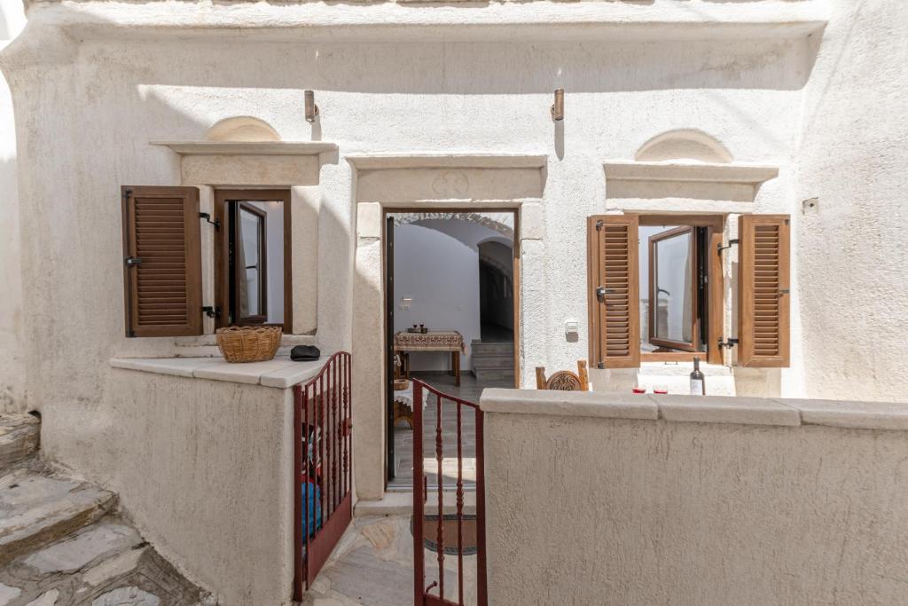 Cette maison blanche dispose de fenêtres en bois et d'un portail. dans l'établissement Casa Estiva Apeiranthos Naxos Apartments, à Naxos Chora