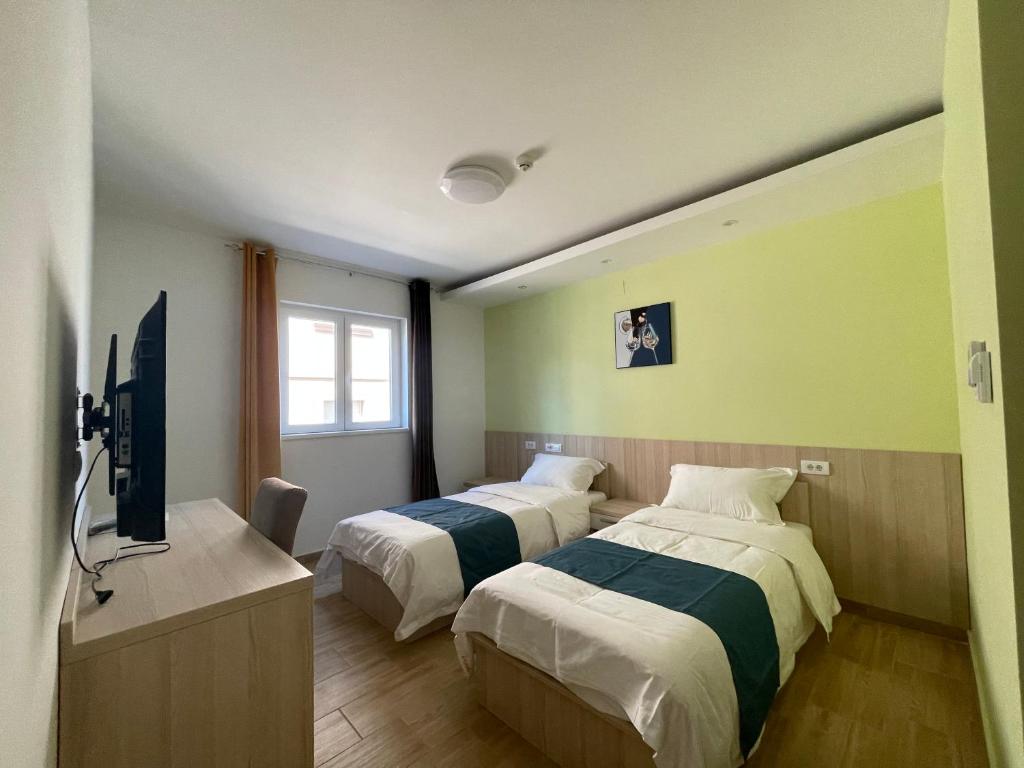 um quarto de hotel com duas camas e uma televisão em home in superior如家 em Surčin