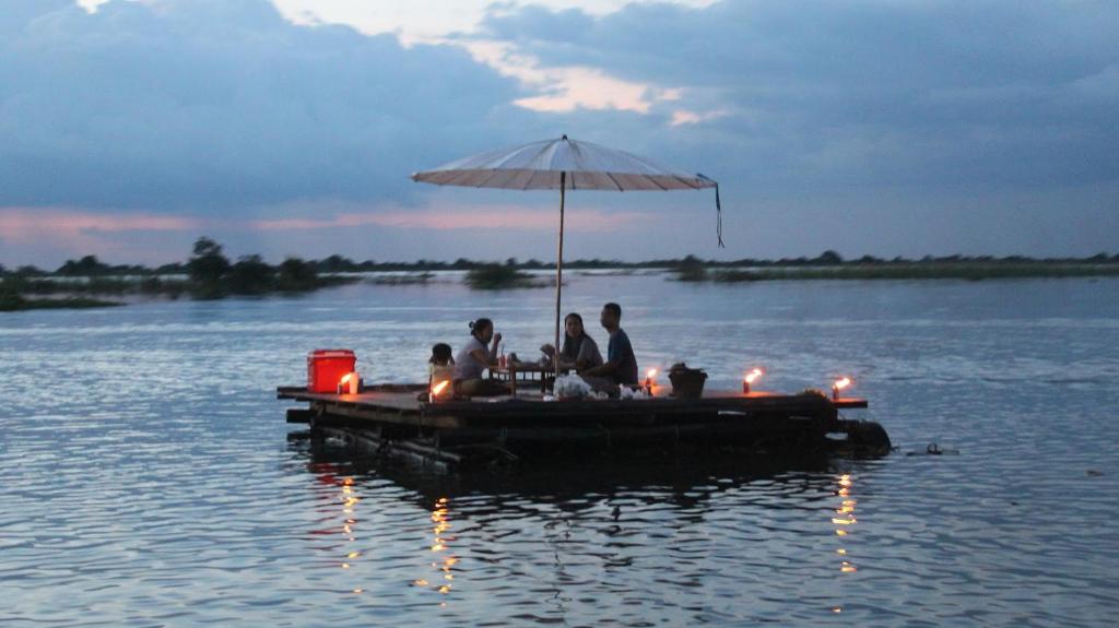 un groupe de personnes assises sur un quai dans l'eau dans l'établissement Mechrey Tonle Camp Site, à Siem Reap