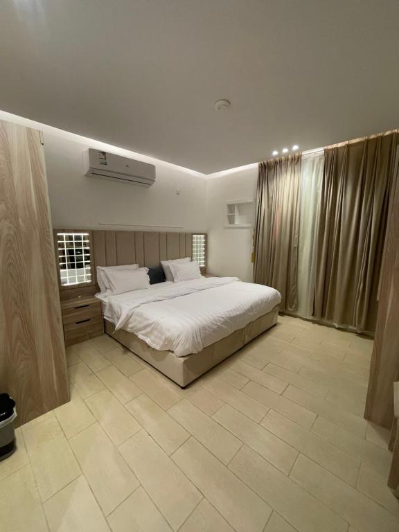 a bedroom with a large white bed and curtains at Friday Suites in AlUla