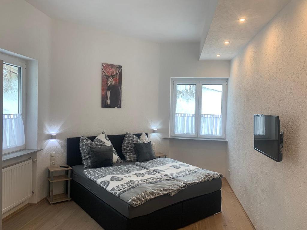 a bedroom with a bed and a tv on the wall at Allgäu Loft Obermaiselstein in Obermaiselstein