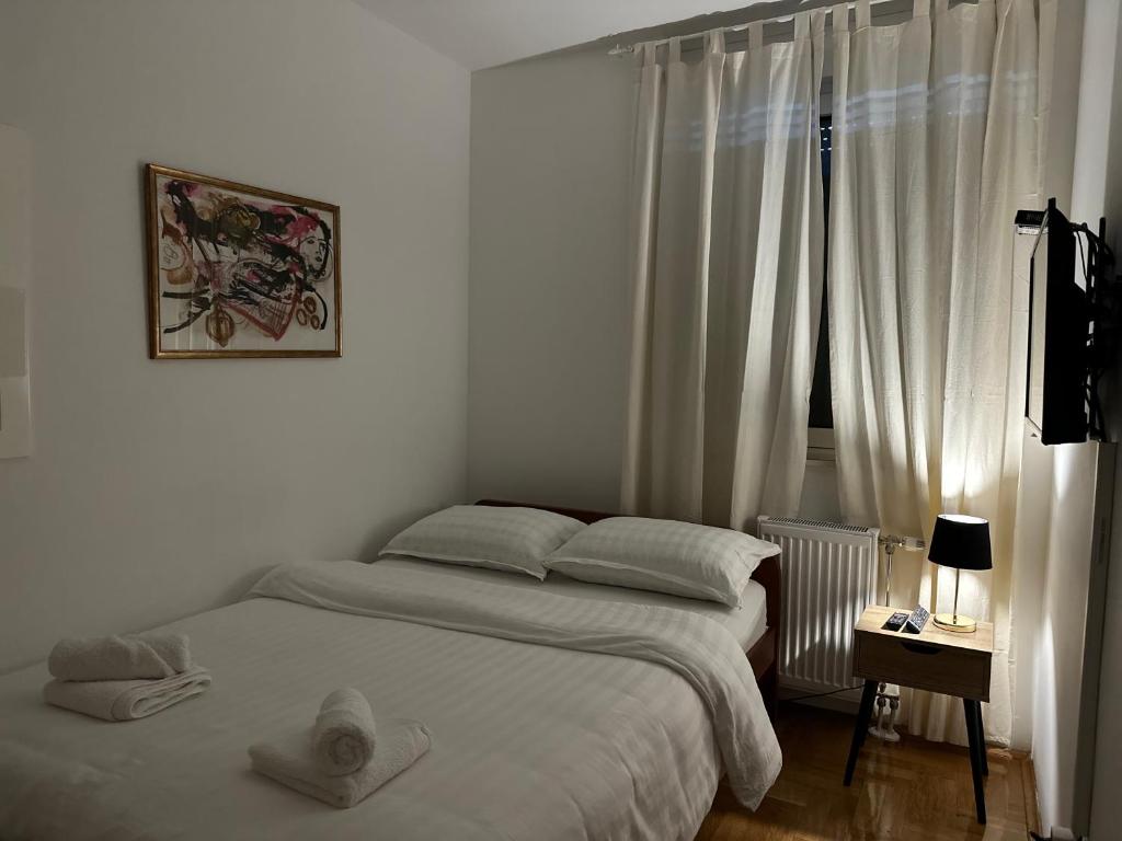 ein weißes Schlafzimmer mit einem Bett und einem Fenster in der Unterkunft The Luxe Loft apartment in Novi Sad