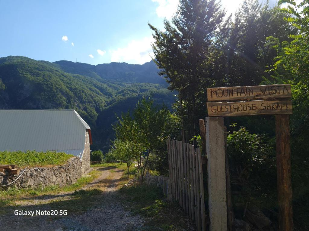 ein Schild, das die Mountain West Street mit Bergen im Hintergrund liest in der Unterkunft Mountain Vista Guesthouse Shkafi in Shkodra
