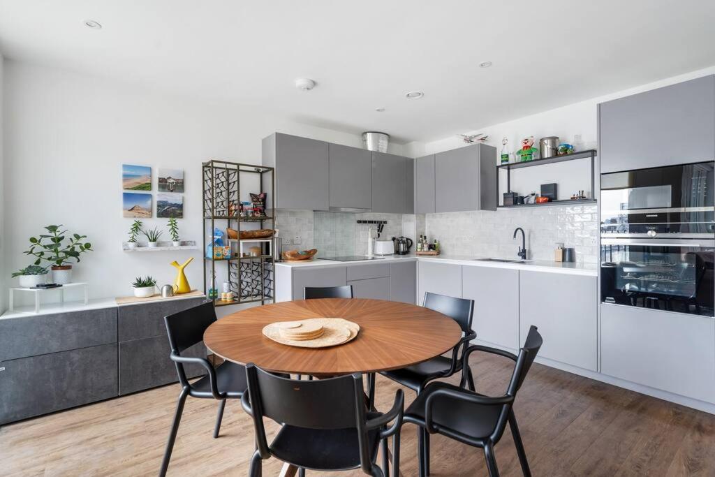 a kitchen with a wooden table and black chairs at Peachy Stays 2-Bedroom Amazing Flat With Balcony in London
