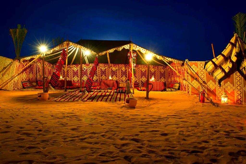a tent on the beach at night with lights at Camp Sahara Dunes in Mhamid