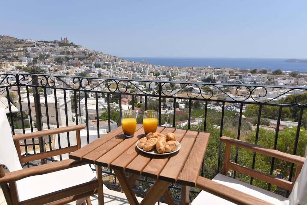 a table with a plate of food and two glasses of orange juice at Απεριόριστη Θέα δίπλα στην πόλη in Ano Syros