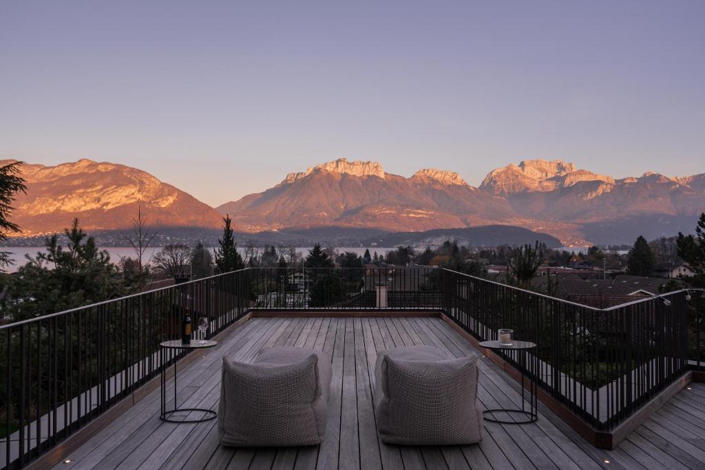a deck with two chairs and a view of mountains at Maison Gokan in Sévrier