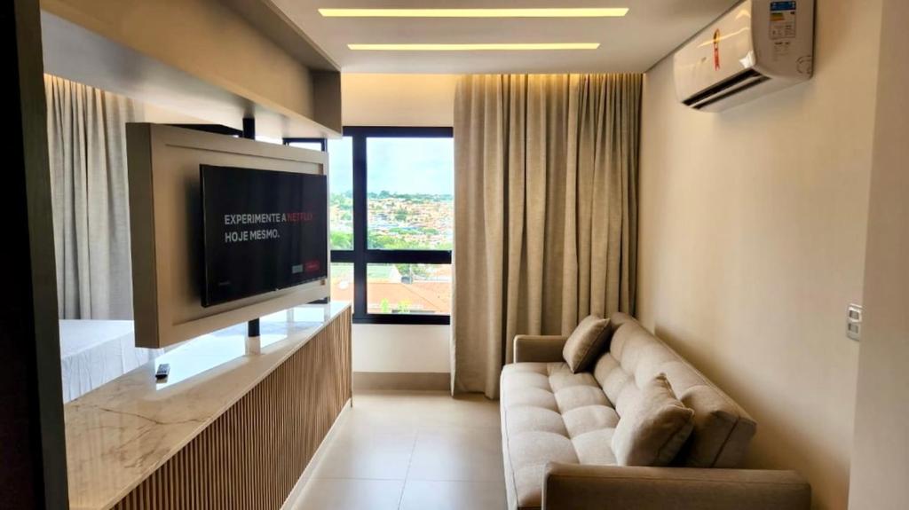 uma sala de estar com um sofá e uma televisão de ecrã plano em Loft Confortável e Luxuoso ao lado do Shopping CG. em Campo Grande
