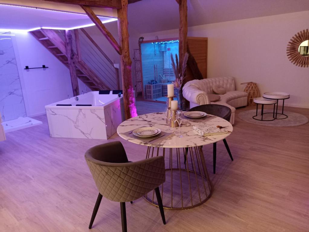 - un salon avec une table et des chaises dans l'établissement Loft blanc (baignoire balnéo et sauna), à Trois-Ponts