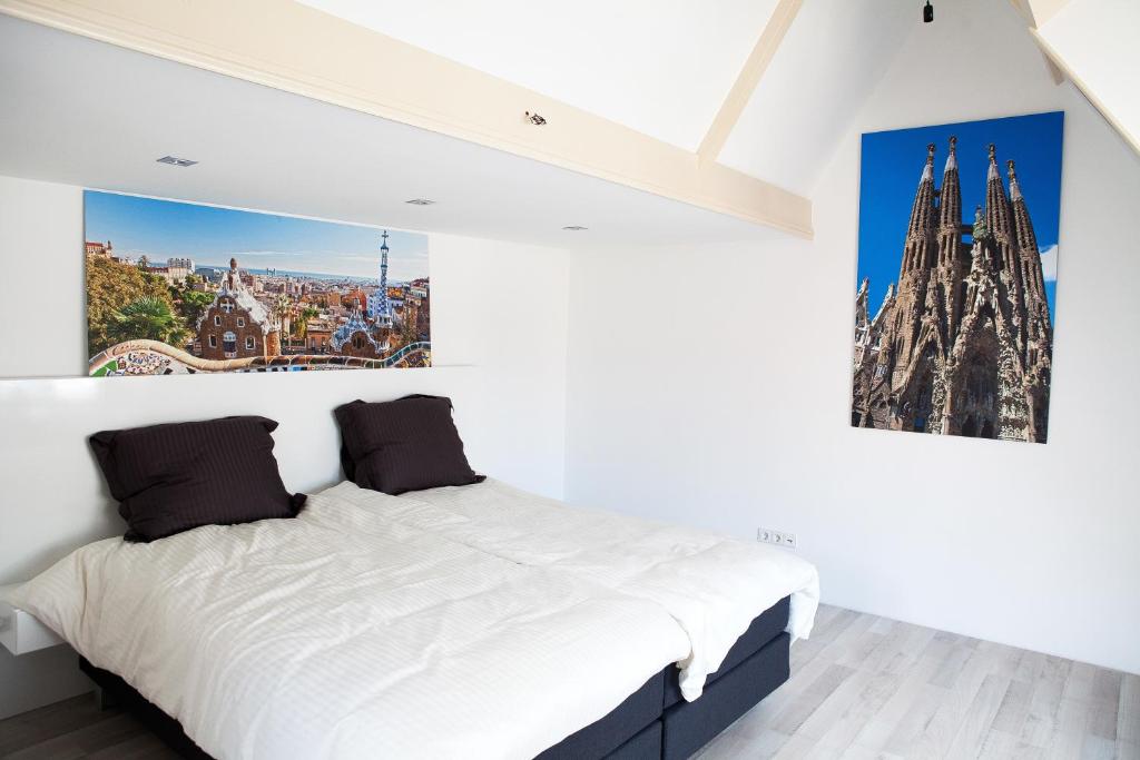 een slaapkamer met een wit bed met een foto aan de muur bij La Casita bed and breakfast in Voorschoten