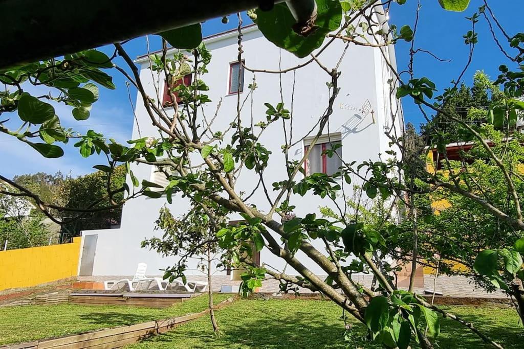 un bâtiment blanc avec un arbre au premier plan dans l'établissement Doniños, maravilla del mundo, te esperamos., à Ferrol