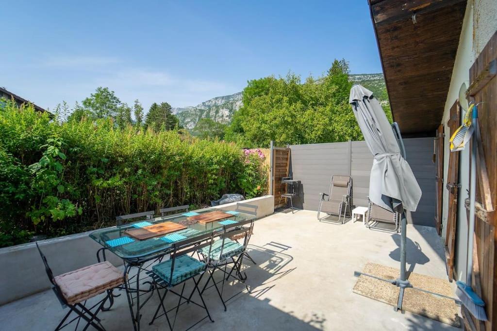 eine Terrasse mit einem Tisch und einem Sonnenschirm in der Unterkunft Appartement in Doussard