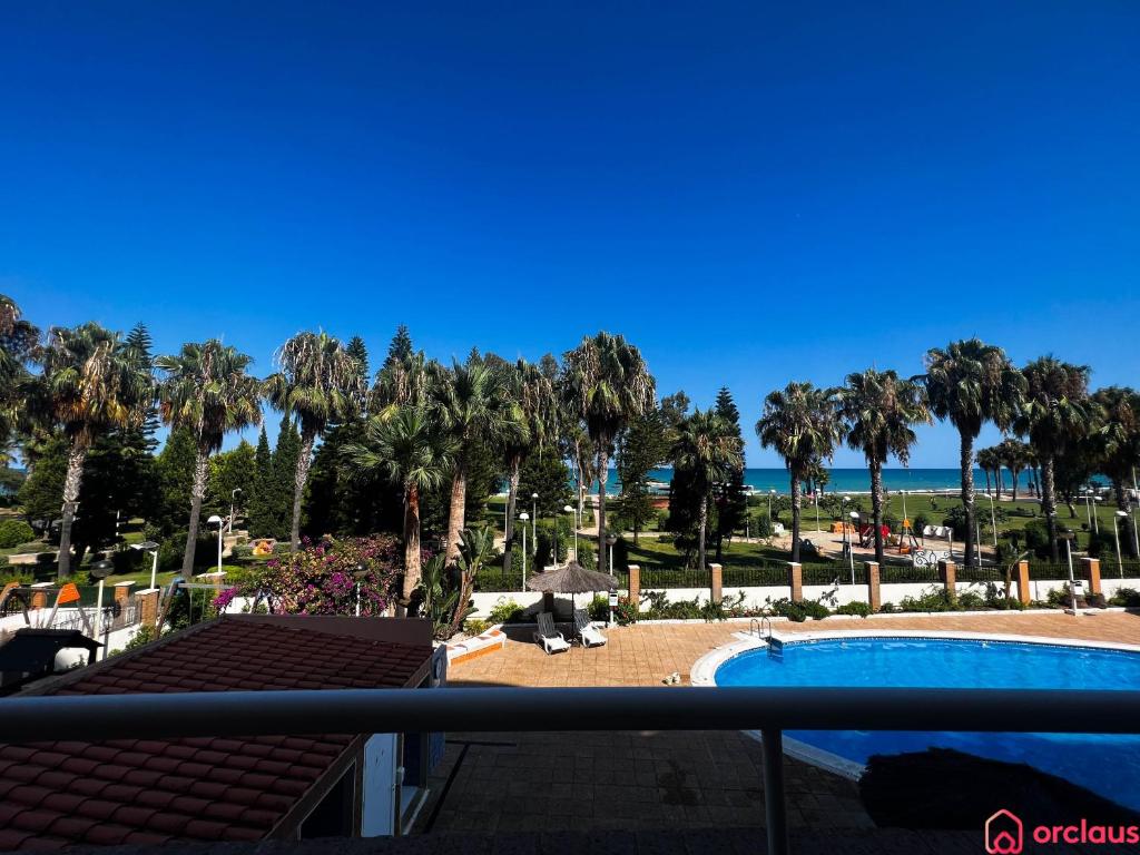 a view from the balcony of a resort with a pool and palm trees at Modern apartment in front of the Mediterranean in Oropesa del Mar