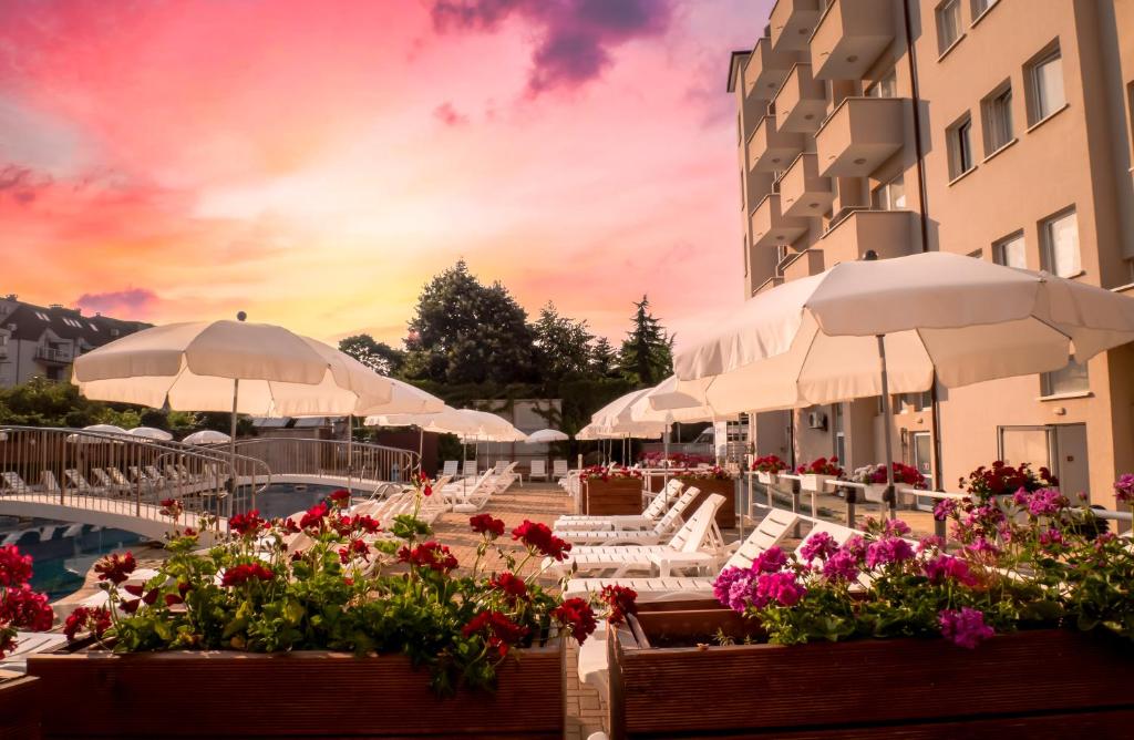 a resort with white chairs and umbrellas and flowers at Hotel Aurora in Saints Constantine and Helena