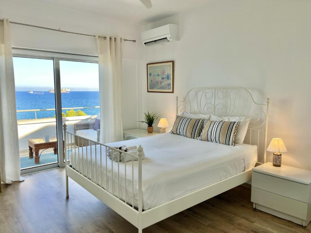 a bedroom with a bed with a view of the ocean at Seaview Beach Apartment Dasoudi in Limassol