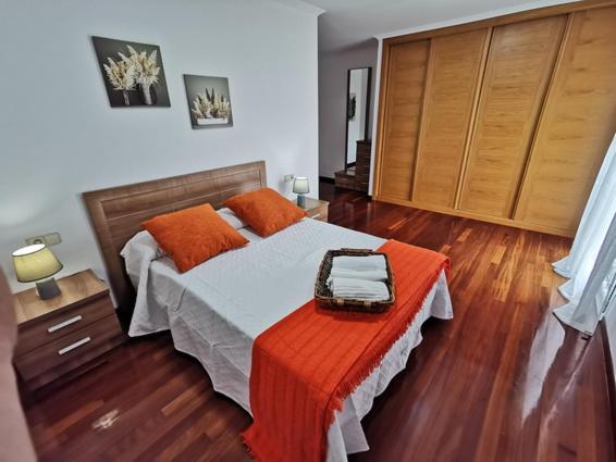 um quarto com uma cama com um cobertor laranja em Apartamento Carrera em Caldas de Reis