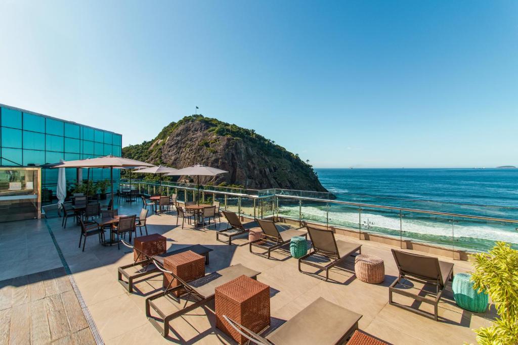 un patio con sillas, mesas y el océano en Arena Leme Hotel, en Río de Janeiro