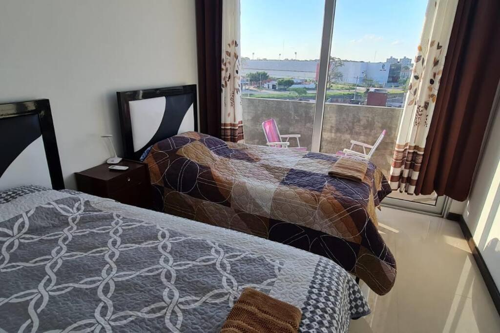 a bedroom with two beds and a large window at Santa Cruz Hermoso Departamento Piscina Toboganes in Santa Cruz de la Sierra