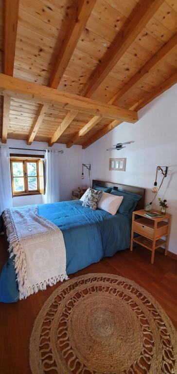 1 dormitorio con cama azul y techo de madera en Casa do Pássaro, en Galegos
