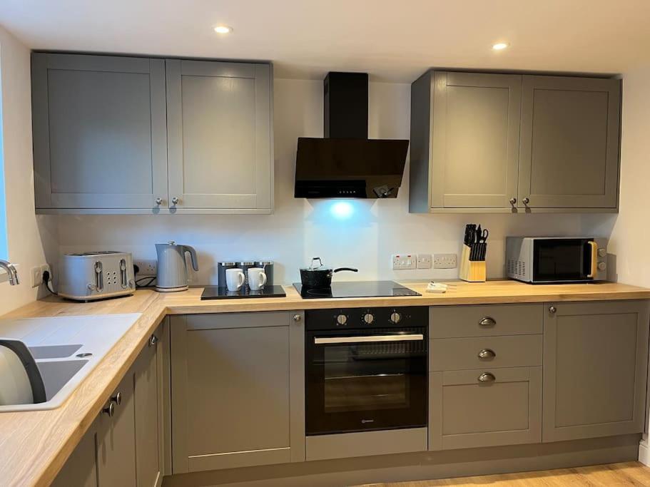 a kitchen with gray cabinets and a stove top oven at Beautiful mid wales cottage in Garth