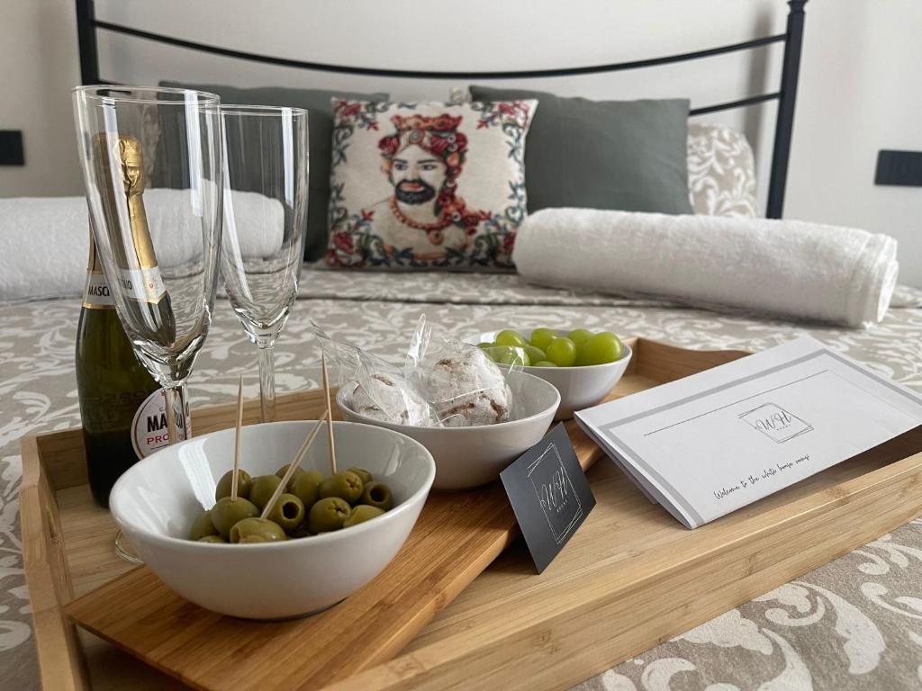 einen Tisch mit einer Flasche Wein und Schalen aus Trauben in der Unterkunft WhiteHouse_Rooms in Calatabiano