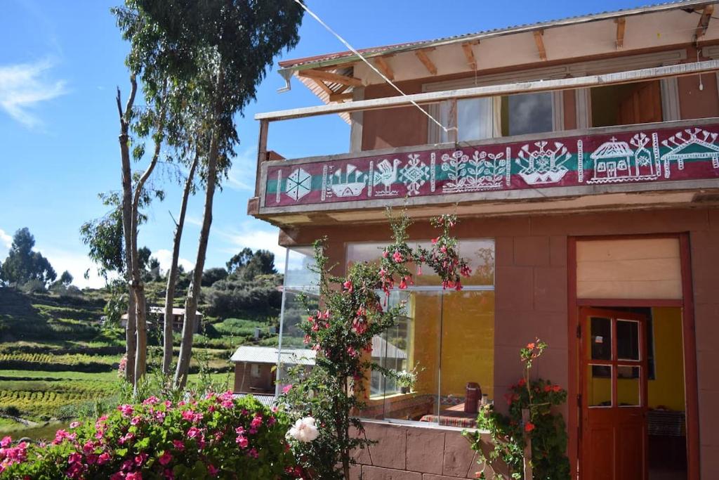 un edificio con un balcón con flores delante en Taquile Sumaq Wasi - Casa de Felipe e Ines, en Huillanopampa