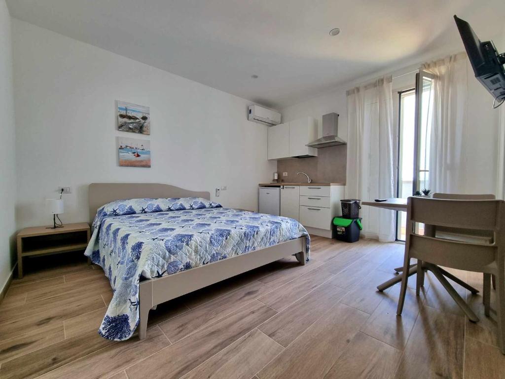 a bedroom with a bed and a desk and a kitchen at La casa di Enzo in Tre Fontane