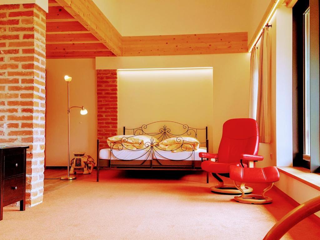 a bedroom with a bed and two red chairs at Sunhill Appartments in Winhöring