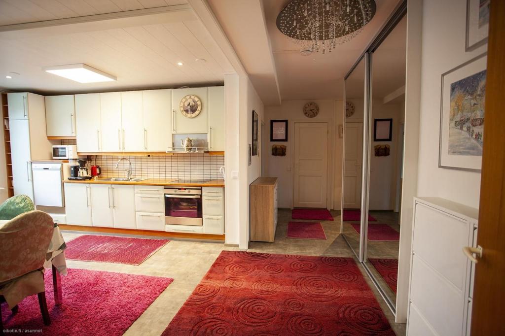 a kitchen with white cabinets and a red rug at Viihtyisä ja rauhallinen keskustan tilava kaksio in Turku