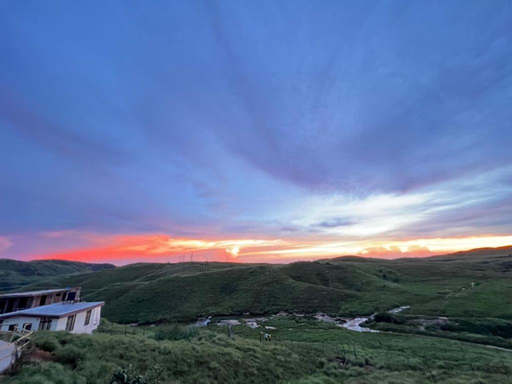 a sunset in the hills with a house and a river at 7 CLOUDS LODGE in Cherrapunji