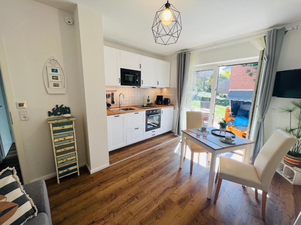 a living room with a table and a kitchen at SeeLund - Meeresrauschen lauschen - ruhiges sonniges Apartment mit Garten und Terrasse nahe Strand und Ostsee in Schönhagen