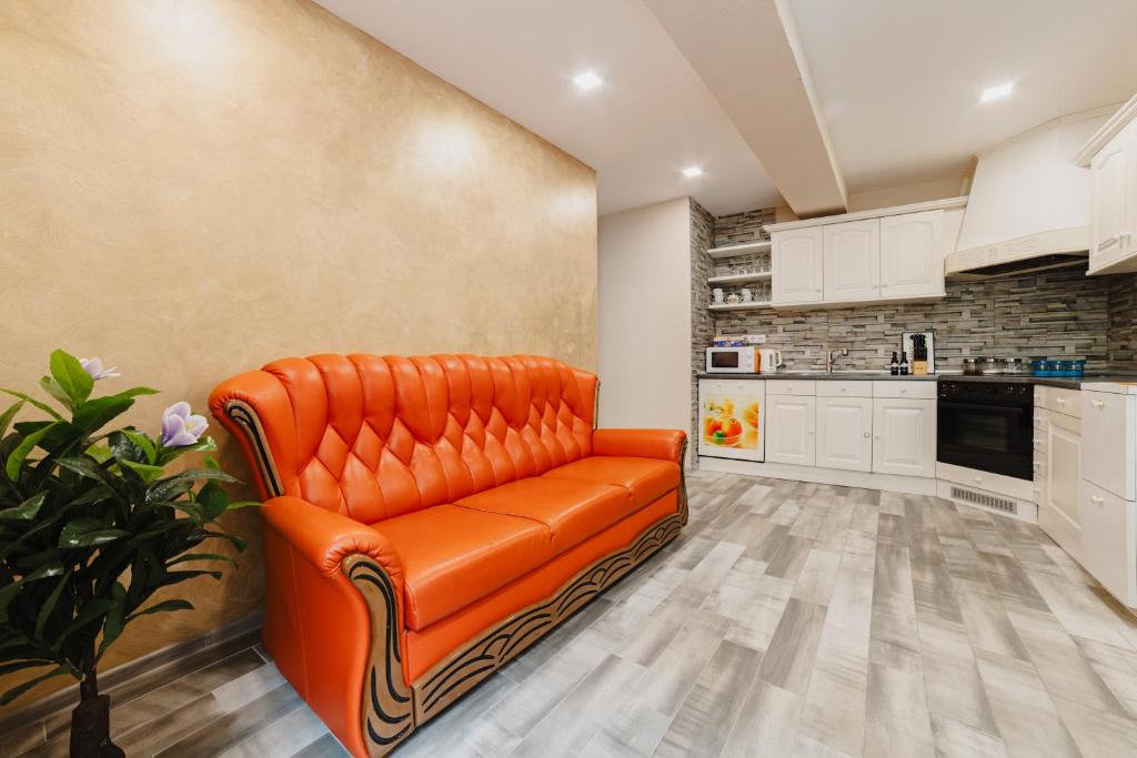 Un sofá de cuero naranja en una cocina con gabinetes blancos. en Noua Oasis BNB with PARKING, en Brasov