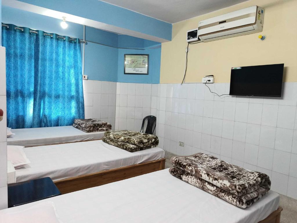 a room with three beds and a flat screen tv at Ananya Homestay in Patna
