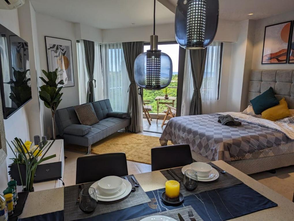 Dominiks Stylish Resort Gem Ocean View Pool Queen Bed at Tambuli 8 Floor Fast Wifi في Maribago: غرفة معيشة مع سرير وطاولة طعام