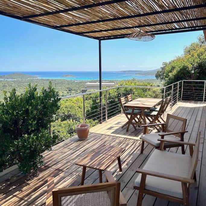 une terrasse en bois avec des tables et des chaises et l'océan dans l'établissement CASA ANPÀ - Mini Villa Vue Mer Ste Lucie de Porto-Vecchio, à Lecci